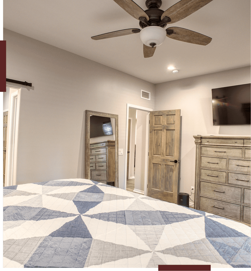 Bedroom with ceiling fan and geometric quilt.